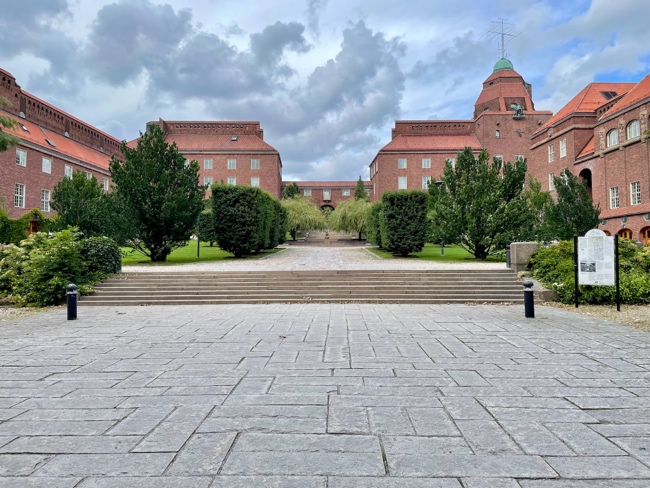 A brick building with trees and a walkwayDescription automatically generated